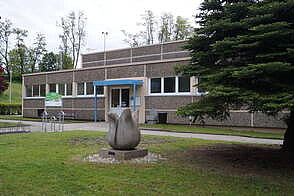 Sporthalle Außenansicht mit Steinskulptur